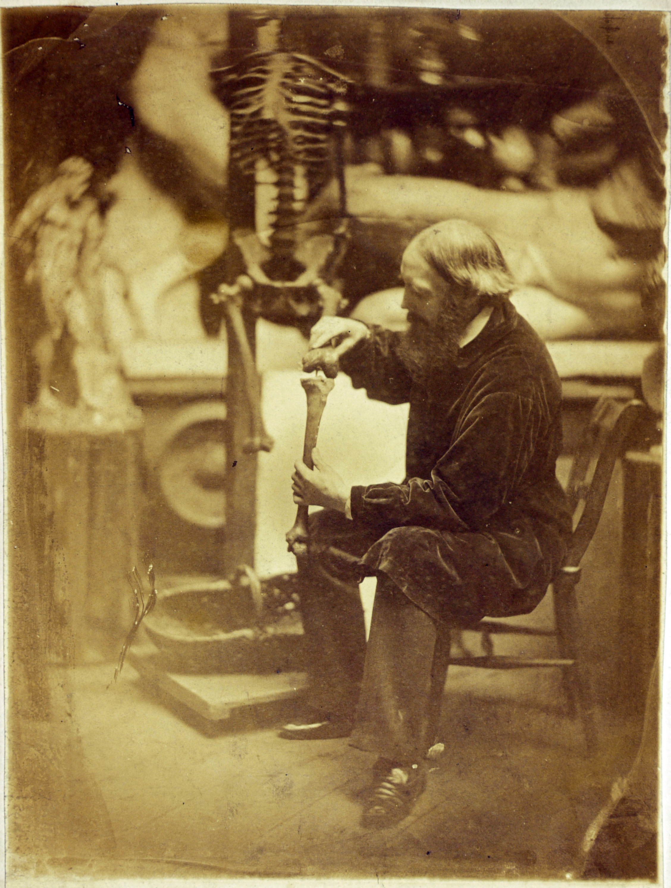 Photographic portrait of a man in an art studio fixing a skeleton