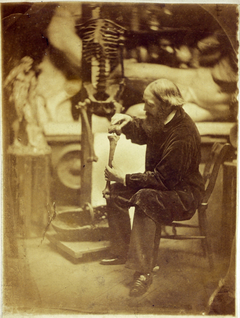 Photographic portrait of a man fixing a skeleton in an art studio
