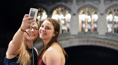 Two students standing in front of the Bridge of Sighs taking a photo