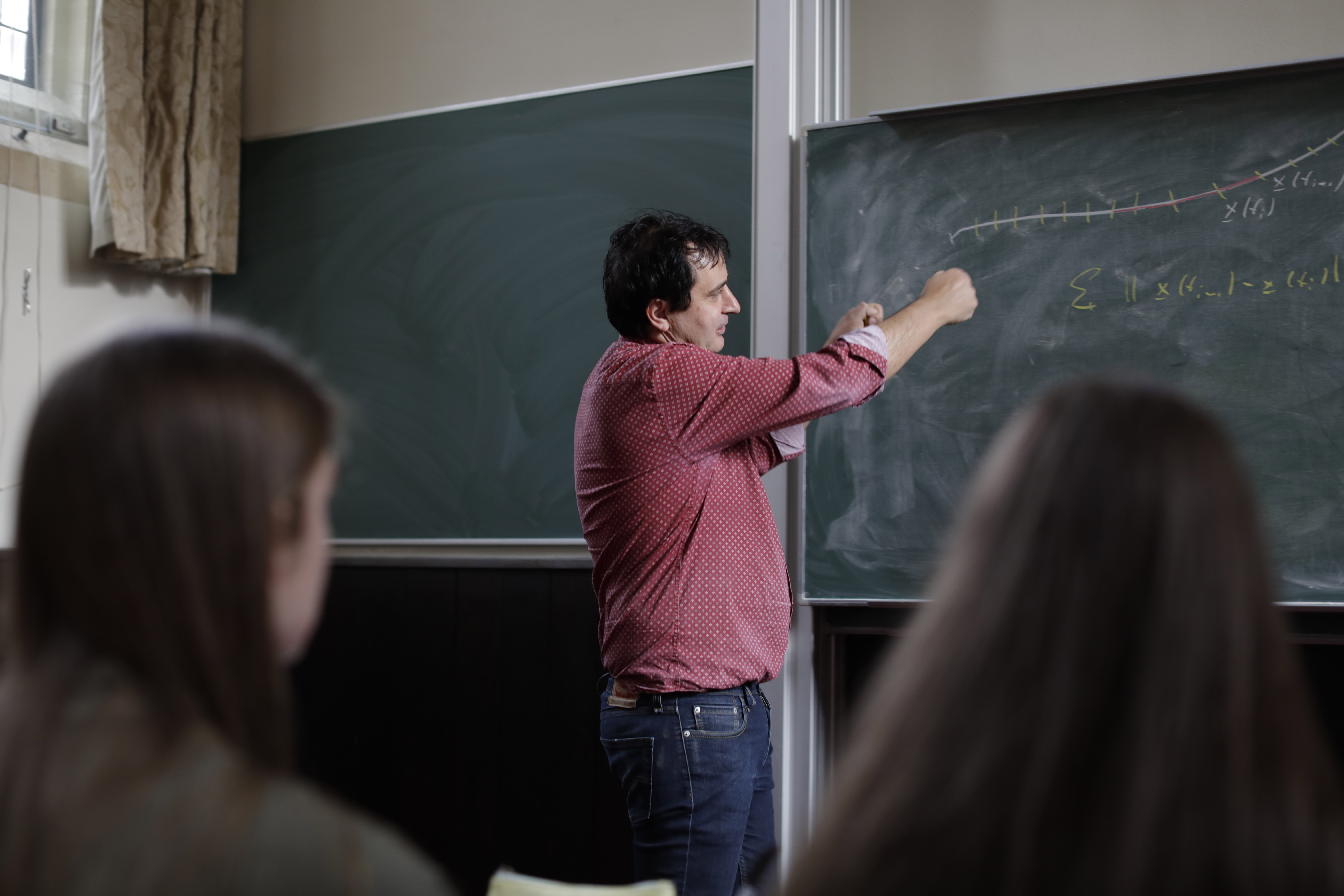 A Tutor explaining a mathematics problem on a blackboard