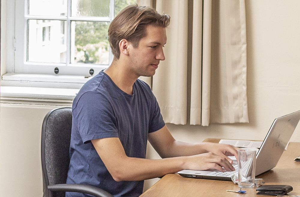 A student works on a laptop in his room