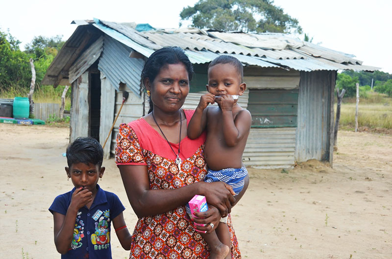 A woman stands in front of her temporary shelter