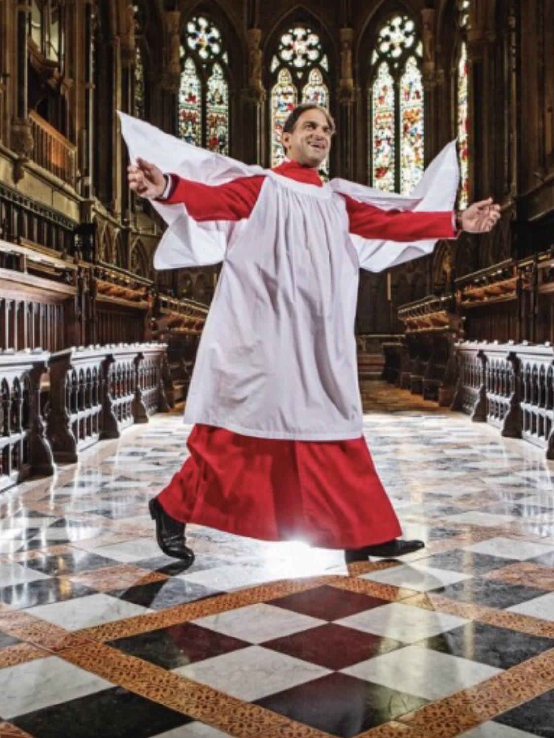 Andrew Nethsingha smiling and leaping in the air in the Chapel