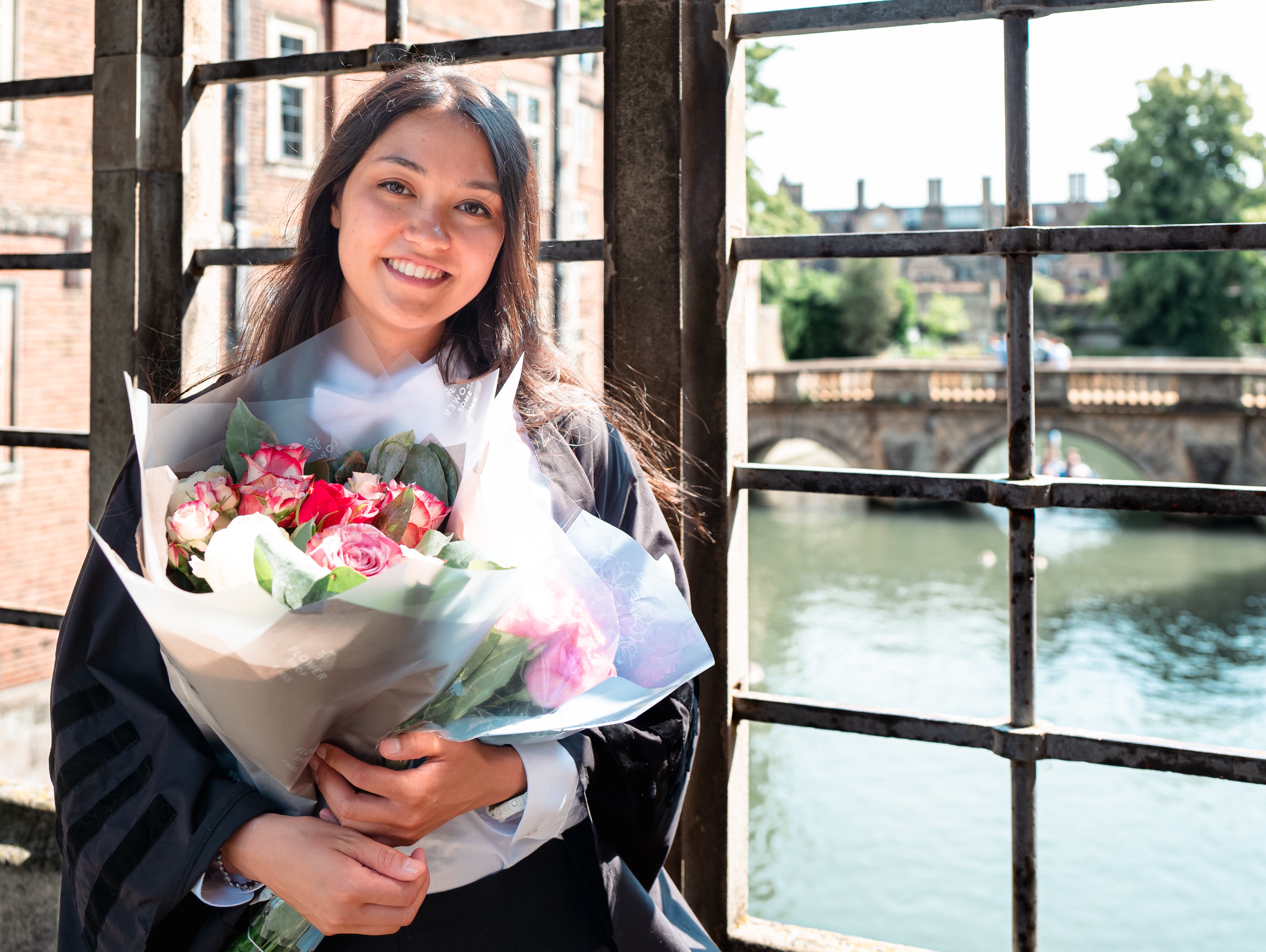 Josephine Cowley photographed standing on the Bridge of Sighs at St John's College with a bunch of flowers