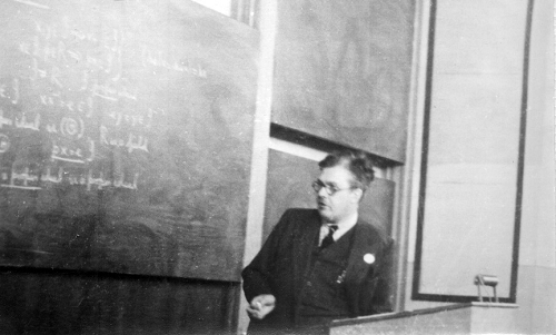 Black and white photo of Frank Smithies at a blackboard covered with calculations