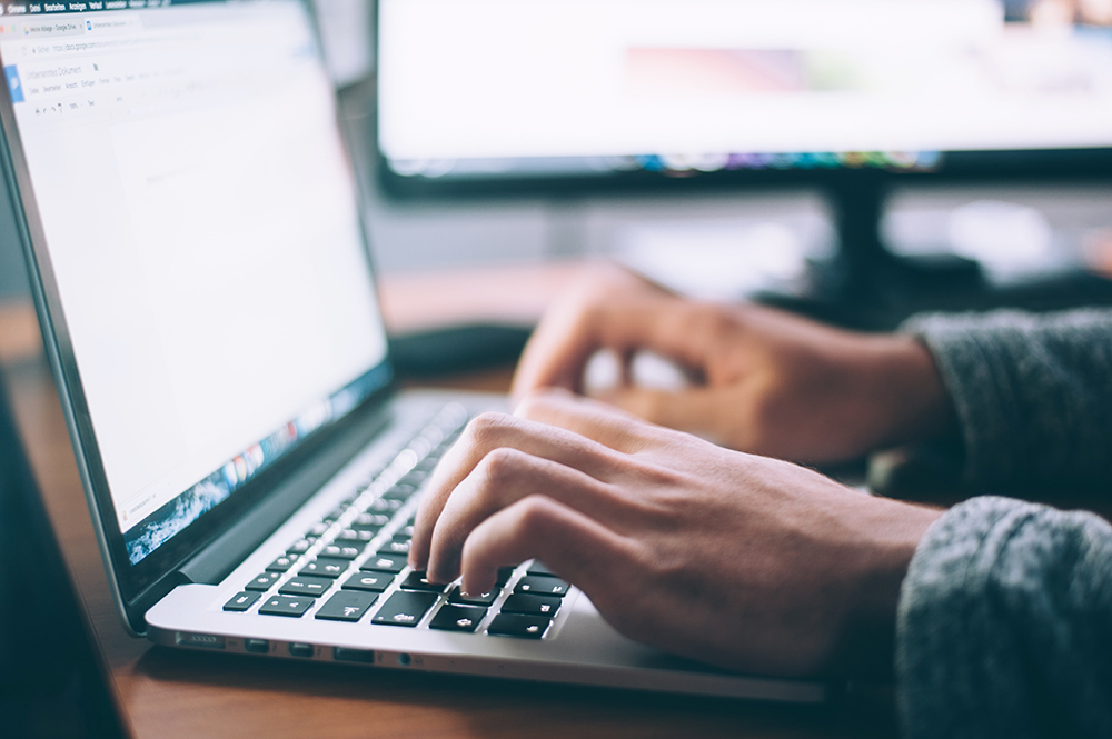 A man types on a laptop keyboard