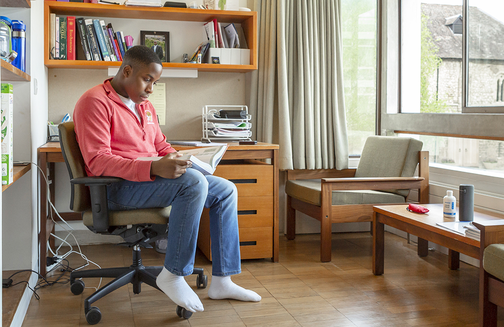 A student studies at the desk in his room