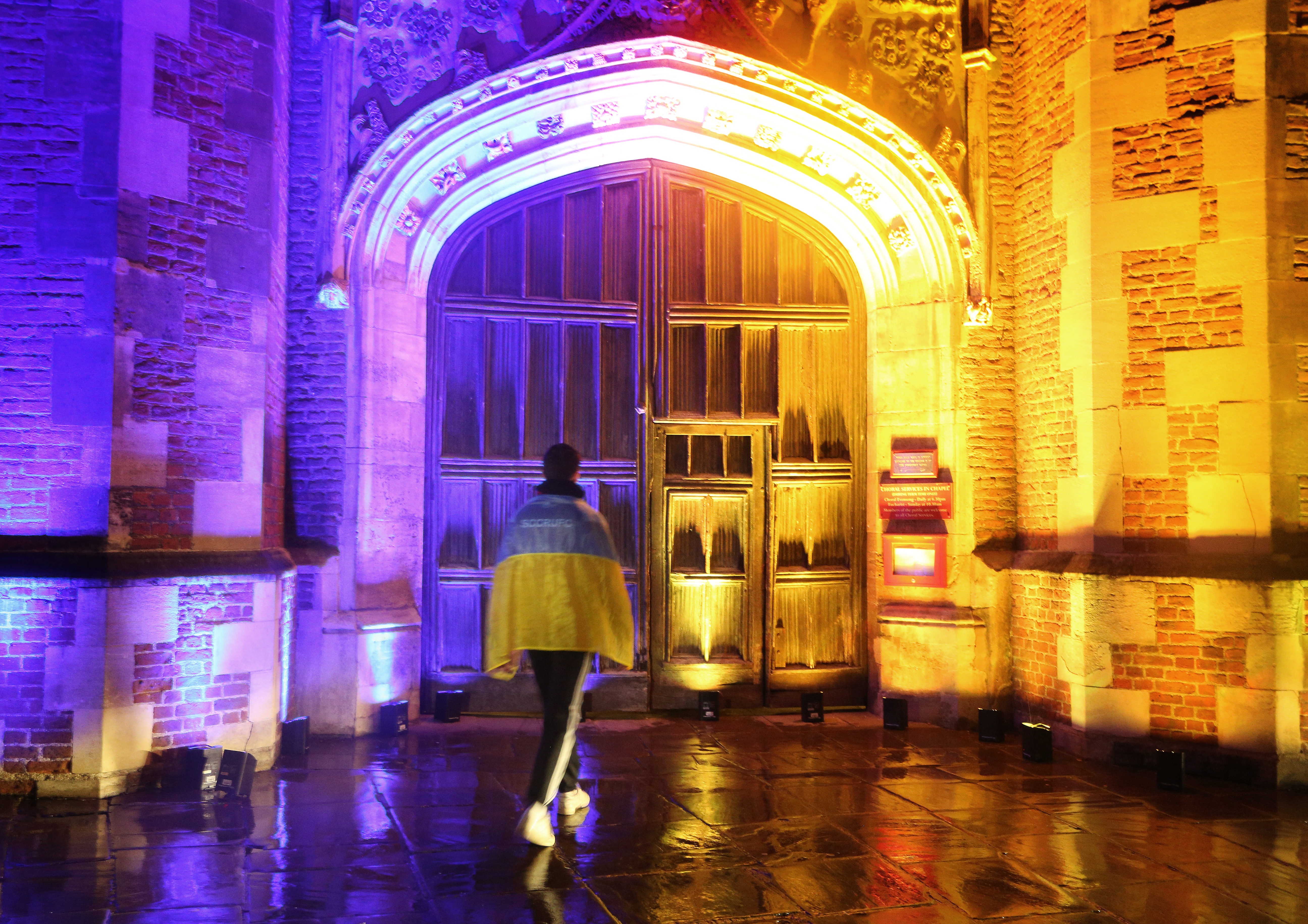 Great Gate illuminated in colours of the Ukrainian flag with a student wrapped in a flag