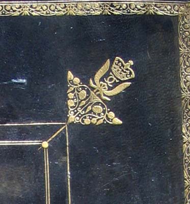 A closeup of a binding showing gold decoration with interlocking letter C.