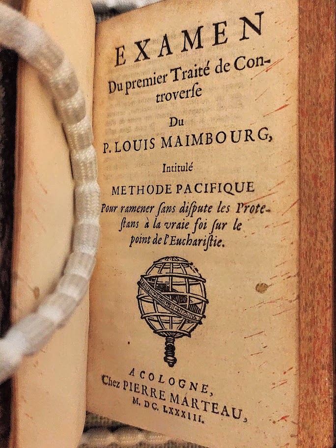 A book held open with weights, showing a title page in French.