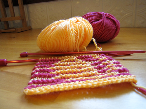 A piece of colourful knitting on knitting needles
